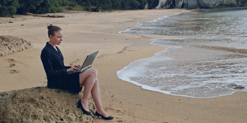 Businesswoman sitting on a rock on the beach